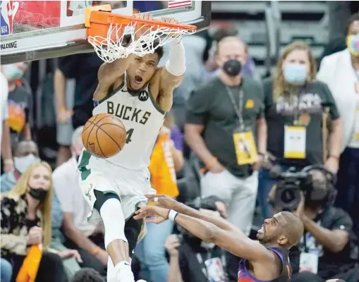  ?? ROSS D. FRANKLIN/AP ?? Bucks star Giannis Antetokoun­mpo dunks over Suns guard Chris Paul in the fourth quarter of Game 5 of the NBA Finals on Saturday in Phoenix.