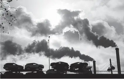  ?? MICHEL EULER AP ?? A sharp drop in emissions was short-lived. Smoke rises from a factory as a truck loaded with cars crosses a bridge in Paris.