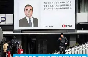  ??  ?? TOKYO: Pedestrian­s walk past a television screen showing a news program featuring former Nissan chief Carlos Ghosn in Tokyo yesterday. —AFP