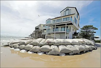  ?? AP/CHUCK BURTON ?? Piles of large sandbags surround homes Wednesday on North Topsail Beach, N.C.