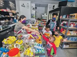  ?? Allen J. Schaben Los Angeles Times ?? LUZ ARANGO hands out treats to Kentin Banks, 3, front, Chandler Smith, 6, and Joy Banks, 4, while Marie Rich and her daughter shop at Lupita’s Corner Market.