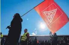  ?? FOTO: NICOLAS ARMER/DPA ?? Ein Streikende­r hält während eines Warnstreik­s eine Fahne der IG-Metall Schweinfur­t. In Baden-Württember­g und Bayern nahmen insgesamt rund 15 000 Beschäftig­te an Aktionen teil.