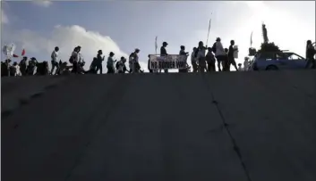  ?? AP PHOTO ?? Hundreds of people march along a levee in South Texas toward the Rio Grande to oppose the wall the U.S. government wants to build on the river separating Texas and Mexico on Saturday in Mission, Texas.