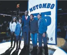  ??  ?? Dikembe Mutombo poses with his family in front of his banner during his jersey retirement ceremony. John Leyba, The Denver Post