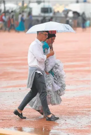  ?? // VALERIO MERINO ?? Dos jóvenes recorren la Feria de Córdoba bajo la lluvia