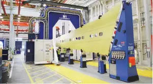  ??  ?? A blue, horseshoes­haped wing assembly machine glides over a yellow wing panel, which will become part of a 737 jetliner, at the Boeing factory in Renton, Washington, in this picture taken March 12, 2015. Boeing Co. has started using a new automated...