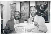  ??  ?? » Dave Carlos (left) hands over a cheque to John Jarratt, winner of a Domark Treasure Hunt. Image courtesy of Dave Carlos.