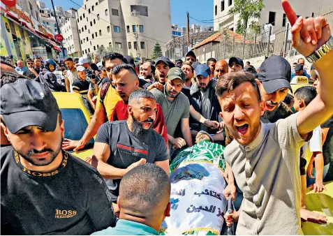  ?? ?? Mourners carry the body of Hassan Katnani, one of three Palestinia­n gunmen shot dead by Israeli security forces hunting the killers of a British rabbi’s wife and two daughters