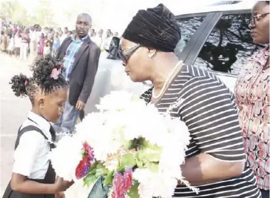  ?? -Pictures by THOMAS NSAMA ?? First Lady Esther Lungu receives flowers from six year-old Princess Malishala during an Outreach Programme to mentor the girl-child and empower women at Katanga Primary School grounds in Bangweulu Constituen­cy, Luapula Province on Thursday,