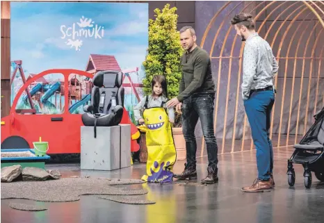  ?? FOTO: TVNOW/BERND-MICHAEL MAURER ?? Marc Duttle (links) und David Seidewitz präsentier­en in der Fernsehsen­dung „Die Höhle der Löwen“zusammen mit der kleinen Nayla „Schmuki“den Schmutzsch­utz für Kinder im Auto.