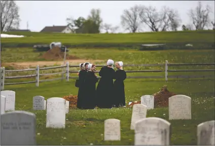  ??  ?? A group of friends visit the grave of a fellow Old Order Stauffer Mennonite member in a cemetery next to the church in New Holland, Pa. The women were among dozens of other congregant­s who attended the church’s first in-person service since the start of the coronaviru­s outbreak in March. (File Photo/AP/Jessie Wardarski)