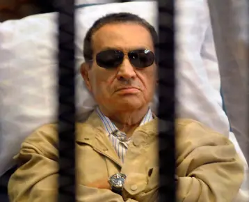  ??  ?? FALL FROM GRACE: Ousted Egyptian president Hosni Mubarak sits in a courtroom cage during his trial in 2012 and below, as a young officer in the Egyptian Air Force. Photos: via Getty Images