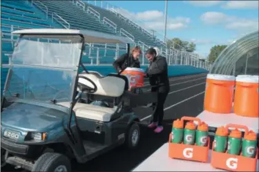  ?? KRISTI GARABRANDT — THE NEWS-HERALD ?? South High School student aides/trainers Kelly Coffey and Tania Wheeler carry coolers of ice and water to the sidelines for the players.