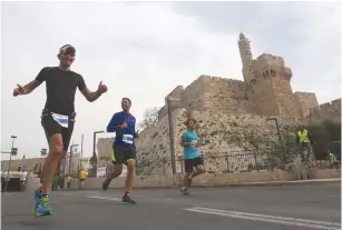  ??  ?? RUNNERS PASS the Tower of David during a race in Jerusalem.