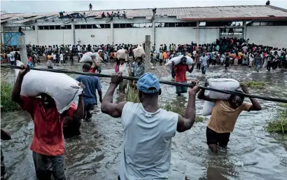  ?? AFP ?? People take part in the looting sacks of Chinese rice from a warehouse which is surrounded by water after the cyclone hit Beira. —