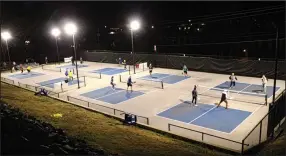  ?? (Special to the Democrat-Gazette/Nancy Raney) ?? Bob Robinson, on the far right court in the yellow sweatshirt, smacks some balls during evening play at Vulcan Pickleball Park in Hot Springs.