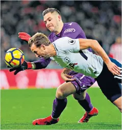  ??  ?? Head first: Harry Kane dives in under pressure from Stoke goalkeeper Jack Butland