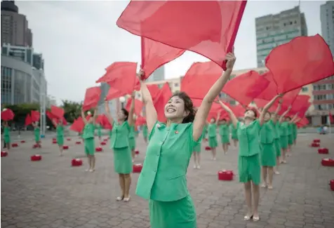  ?? — AFP ?? A propaganda troupe perform a flag-waving routine outside the central railway station in Pyongyang on Wednesday.