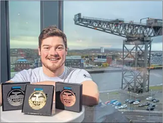  ??  ?? Scott McLay alongside the medals on offer at Tollcross this week, with the Finnieston Crane in the background