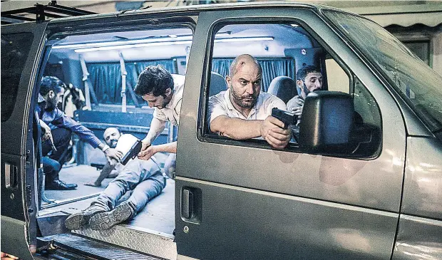  ?? YES STUDIOS ?? Lior Raz, the co- creator of Fauda and actor portraying Doron Kavillio, points his weapon out the window of a van in a scene from Season 1.
