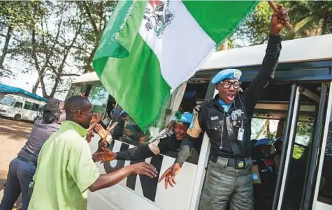  ?? Reuters ?? ■ Members of the Formed Police Unit from Nigeria deployed with UNTIL greet local people while going to the airport in Harbel, Liberia. Headway in reforming security forces has been undermined by little progress in tackling the country’s legacy of war.