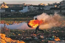  ?? AFP ?? Stones, slingshots and burning vehicle tyres, above, are all Palestinia­n youths have to face fully armed Israeli troops