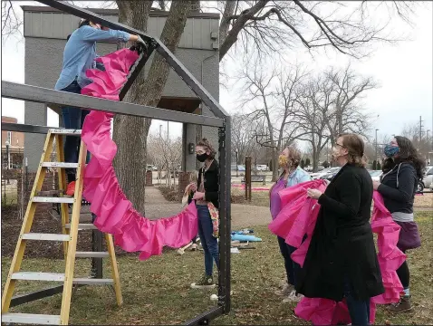  ?? (Courtesy Photos) ?? A team of volunteers install the sculpture “Guide These, My Hands,” on Feb. 27 in Bentonvill­e’s Train Station Park.
