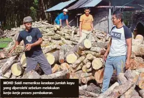  ??  ?? MOHD Saidi memeriksa keadaan jumlah kayu yang diperolehi sebelum melakukan kerja-kerja proses pembakaran.