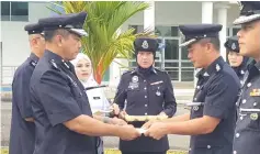  ??  ?? Stanley (left) presents a certificat­e of acknowledg­ement to a police officer during the parade.