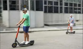  ?? Steve Mellon/Post-Gazette ?? Two men ride Spin scooters on Fourth Avenue, Downtown, on Friday. The newest way to ride around Pittsburgh has taken off, with thousands of rides taken each day. But the city has still been getting complaints about the electric scooters.