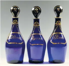  ??  ?? A set of three small club shaped decanters in blue glass decorated with gilded faux labels for Hollands, brandy and rum. They date from 1790