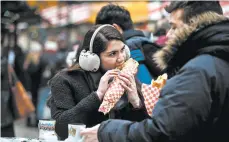  ?? CAMILLE FINE/CHICAGO TRIBUNE ?? Patricia Rivero, 24, and Orlando J. Rivero, 25, eat German food and drink out of souvenir boot mugs at Chicago’s Christkind­lmarket.