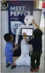  ?? THE ASSOCIATED PRESS ?? James Mak, left, and Marco Mak touch Pepper the robot at Westfield Valley Fair shopping center in San Jose, Calif. Pepper greets shoppers and has the potential to send messages geared to people’s age and gender through facial recognitio­n.