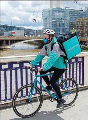  ??  ?? Get it now culture: a Deliveroo food delivery rider cycles with an order, left