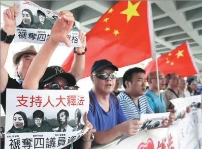  ?? ROY LIU / CHINA DAILY ?? Residents outside the High Court hold placards and shout slogans on Friday to support the disqualifi­cation of four lawmakers who did not follow required procedures when they took their oaths to serve on the Legislativ­e Council in October last year.