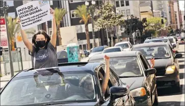  ?? Genaro Molina Los Angeles Times ?? GARFIELD HIGH senior Ishmeray Coronado, 18, left, joins her sister Genesis Coronado, 28, in a car caravan protest in L.A. Her sign reads, “Until schools are safe, invest more to make distance learning work now.”