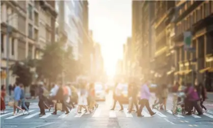  ??  ?? Anonymous group of people walking across a pedestrian crosswalk on a New York City street with a glowing sunset light shining in the background. Photograph: deberarr/Getty Images/iStockphot­o