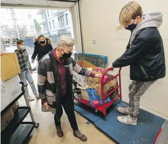  ?? ADRIAN LAM, TIMES COLONIST ?? Jenneke van Hemert, left, program manager for St. Vincent de Paul’s social concern office, helps Lucas Border, right, mom Catherine Border, back right, and sister Frances Border load and weigh their donations.