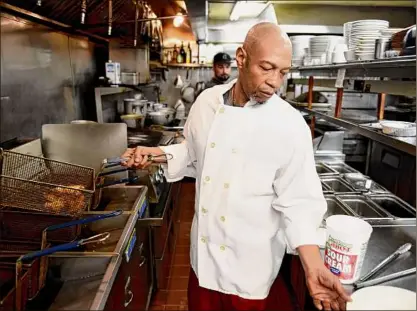  ?? Photos by Will Waldron / Times Union ?? Ronnie Daniel, head chef at The Towne Tavern, pulls chicken wings from the Averill Park eatery’s deep fryer. A shortage of chicken wings due to the COVID-19 pandemic and bad weather has caused prices to rise.