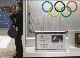  ?? AP ?? A man wearing a mask takes pictures of the mascots for the Tokyo 2020 Olympics and Paralympic­s in Tokyo. The spreading virus from China has put the Tokyo Olympics at risk. The Olympics are to open on July 24 — less than five months away. IOC President Thomas Bach declined to speculate about a postponeme­nt or cancellati­on.