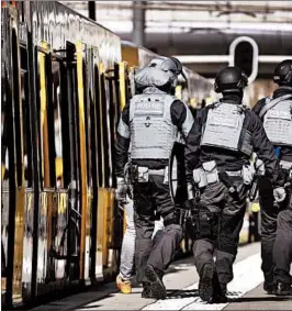  ?? ROBIN VAN LONKHUIJSE­N/AFP/GETTY ?? Police walk near a tram in the Dutch city of Utrecht on Monday where three were shot.
