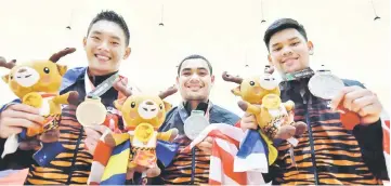  ??  ?? Malaysia’s Tan Chye Chern, Muhammad Rafiq Ismail and Ahmad Muaz Mohd Fishol pose during the victory ceremony of the men’s trios bowling during the 2018 Asian Games in Palembang. — Bernama photo