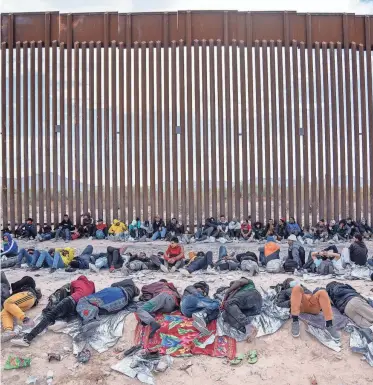  ?? ?? Migrants and asylum seekers wait to be picked up and processed by U.S. Border Patrol agents along the U.S.-Mexico border about a mile west of Lukeville, Ariz., on Dec. 4.