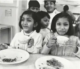  ??  ?? Ugandan Asian children enjoy a meal at the canteen of the former Royal Military Police Barracks in Kensington, London, 1972. On first arriving in the UK, newcomers were often housed in military premises