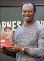  ?? SETH WENIG — THE ASSOCIATED PRESS ?? Golfer Tiger Woods holds up a copy of his new book at a book signing in New York, Monday.