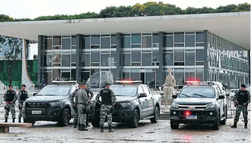  ?? FOTOS: AFP ?? Oficiales y vehículos de la Fuerza Nacional de Seguridad montan guardia frente al Palacio de Planalto en Brasilia para resguardar al personal de gobierno, que es amenazado por los seguidores del expresiden­te Jair Bolsonaro.