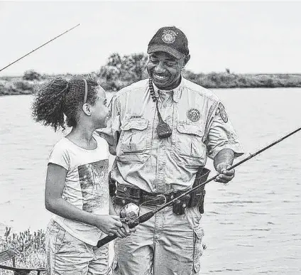  ?? Courtesy Photo / Texas Parks & Wildlife Department ?? Texas Parks & Wildlife game wardens work day and night all year round chasing poachers and other criminals. But they also take the time to teach youngsters about the outdoors, such as this officer showing a girl proper casting technique at a Go Fish event.