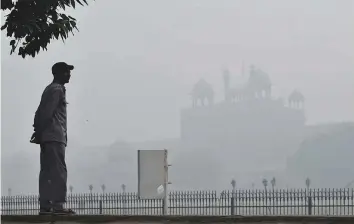  ?? Bloomberg ?? A man in front of a building shrouded in smog in New Delhi last November. With winter just around the corner, pollution levels are set to reach alarming heights in the city — yet again.