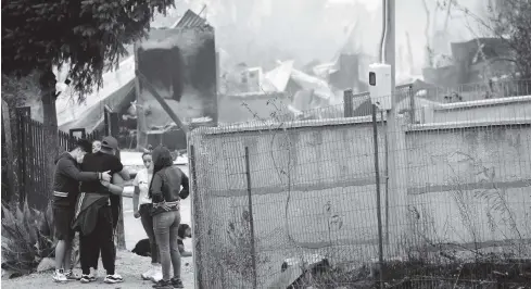  ?? FOTO: AFP ?? Familia llora junto a una casa destruida durante un incendio en Santa Juana, Concepción, Chile.