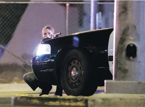  ?? JOHN LOCHER / THE ASSOCIATED PRESS ?? A police officer takes cover behind a police vehicle during the shooting near the Mandalay Bay resort in Las Vegas on Sunday.